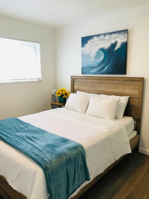 A bedroom with a bed, nightstand and window.