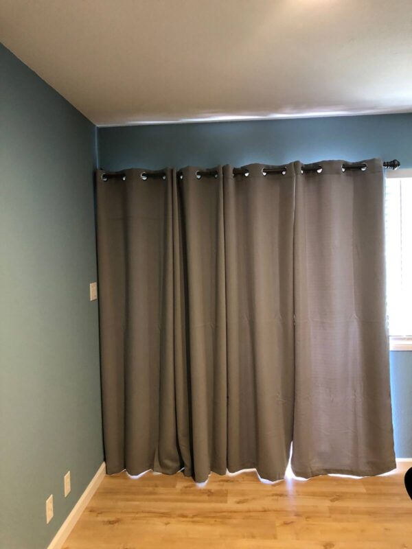 A room with two curtains and a window.