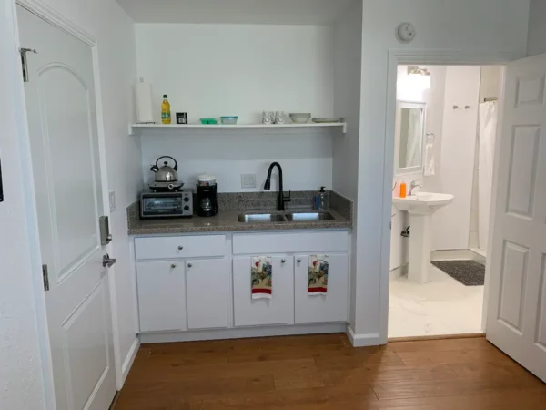 A kitchen with white cabinets and wood floors.