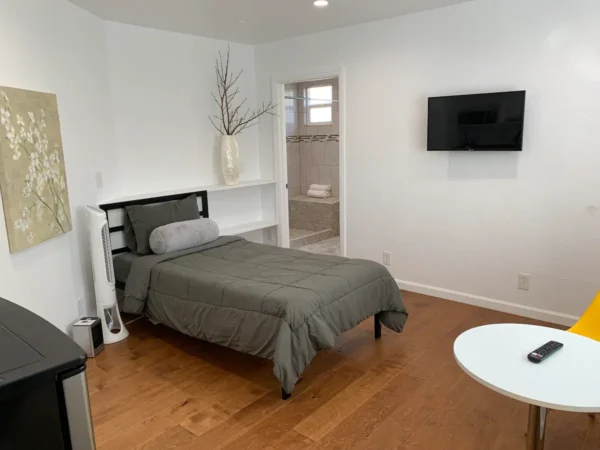 A bedroom with a bed, tv and a chair.