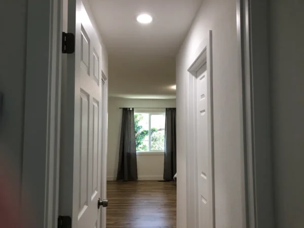 A hallway with white doors and wooden floors.