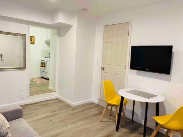 A room with a desk and a tv on the wall