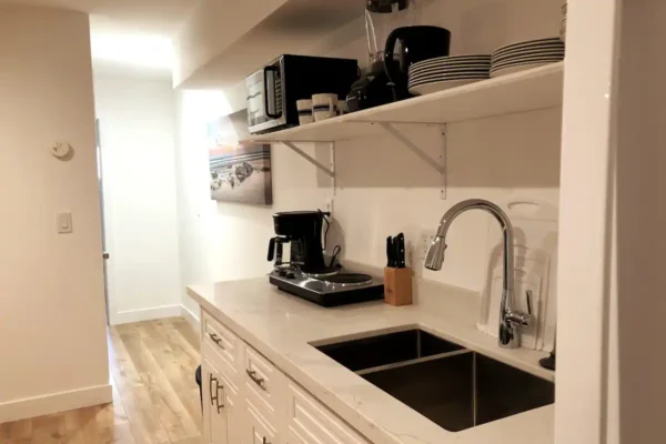 A kitchen with white cabinets and black sink.