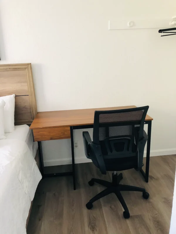 A desk and chair in front of the bed.