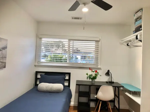 A bedroom with a desk and chair in it