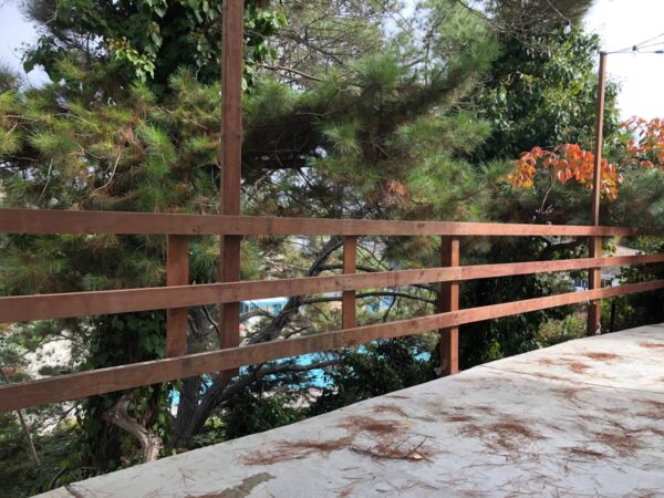 A wooden fence is shown with trees in the background.