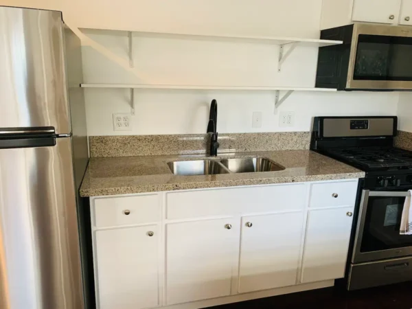 A kitchen with white cabinets and granite counter tops.