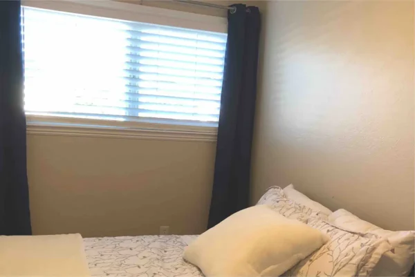 A bed room with a white bedspread and pillows