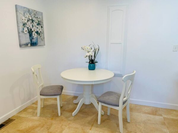 A white table and two chairs in a room.