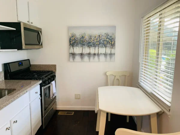 A kitchen with white cabinets and a table in the corner.