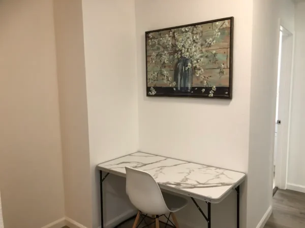 A white desk and chair in front of a painting.