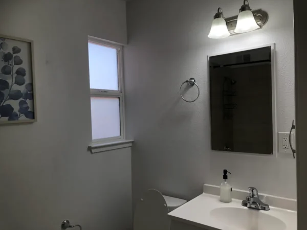 A bathroom with a sink, mirror and window.