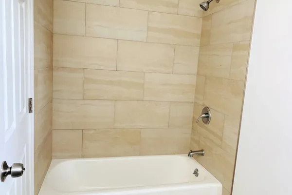 A bathroom with a tub and tiled walls.