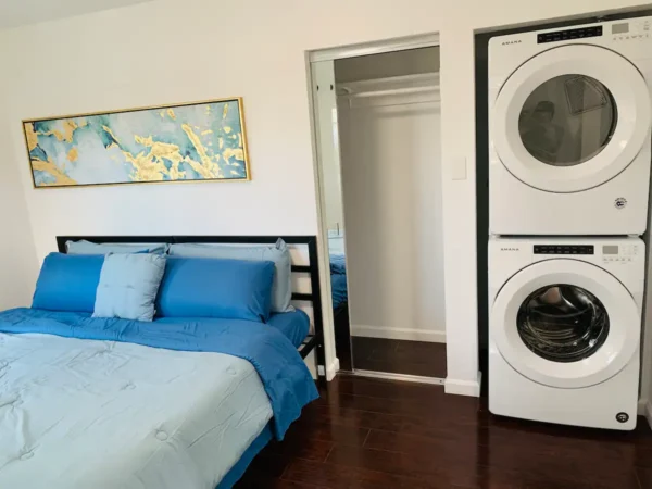 A bedroom with a bed and two washing machines.