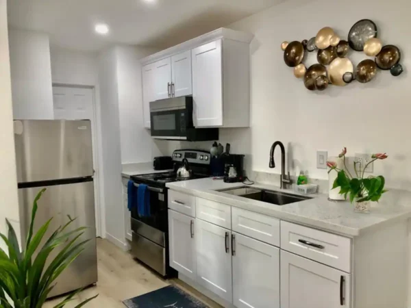 A kitchen with white cabinets and black appliances.