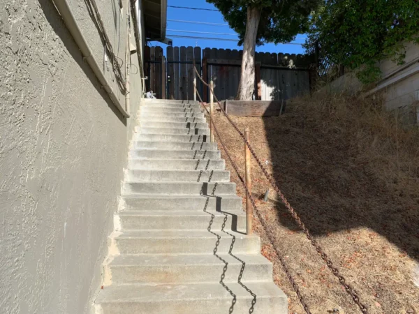 A cat is sitting on the railing of stairs.