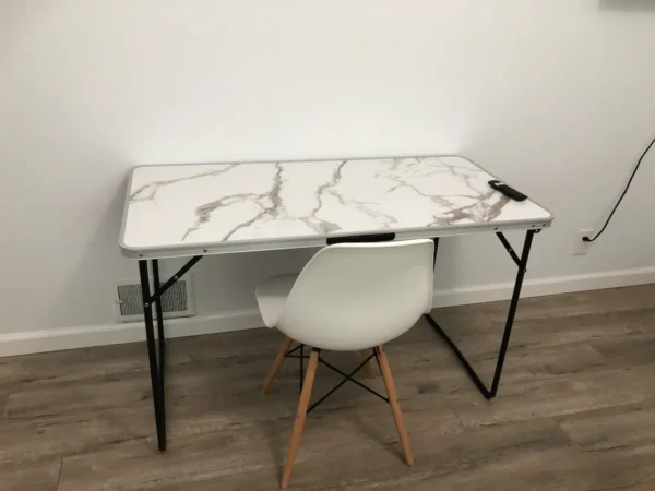 A white chair and table in front of a wall.