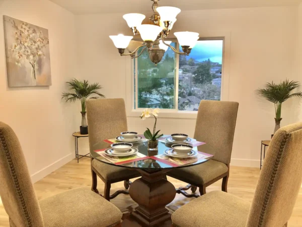 A dining room table with four chairs and a chandelier.