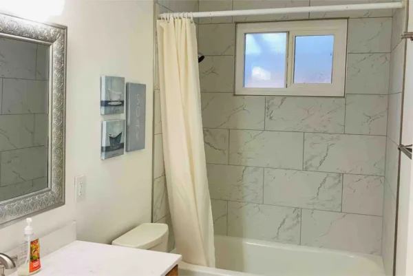 A bathroom with a tub, toilet and shower.