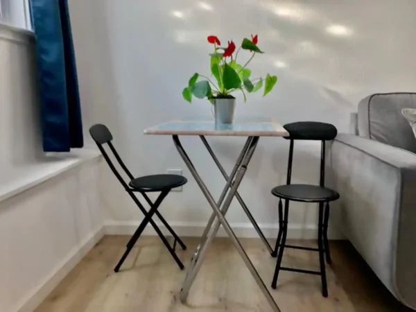 A table and two chairs in front of a window.