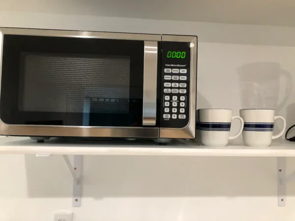 A microwave oven sitting on top of a shelf.