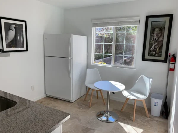 A kitchen with two white chairs and a table