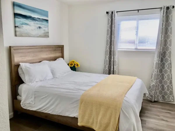 A bedroom with a bed, window and wooden headboard.