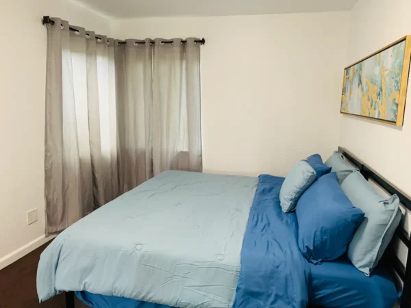 A bedroom with blue sheets and pillows on the bed.