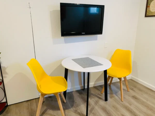 A table and two chairs in front of a tv.