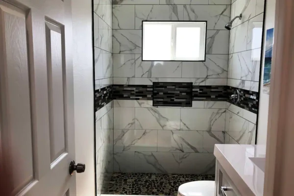 A bathroom with marble walls and black accents.