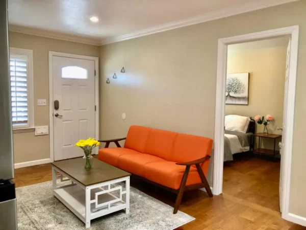 A living room with orange couch and white table