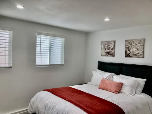 A bedroom with white walls and red accents.