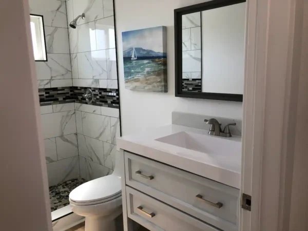 A bathroom with white tile and marble walls.