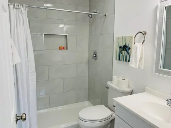 A bathroom with white tile and a toilet.