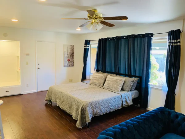 A bedroom with a bed, ceiling fan and window.