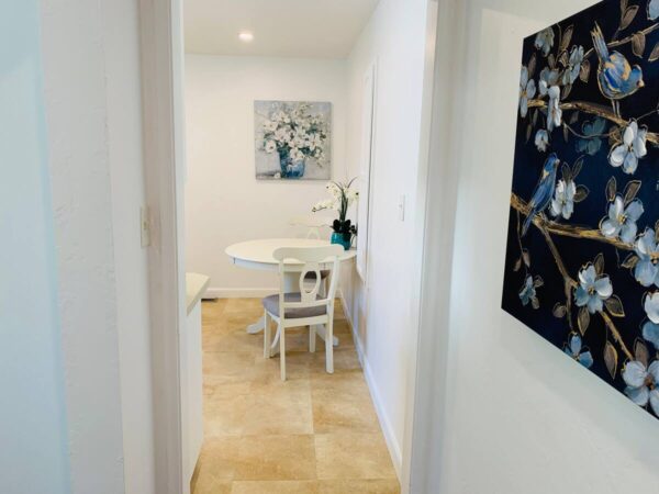 A white table and chairs in the hallway of a home.