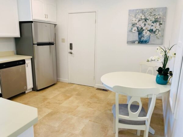 A kitchen with white walls and tile floors.