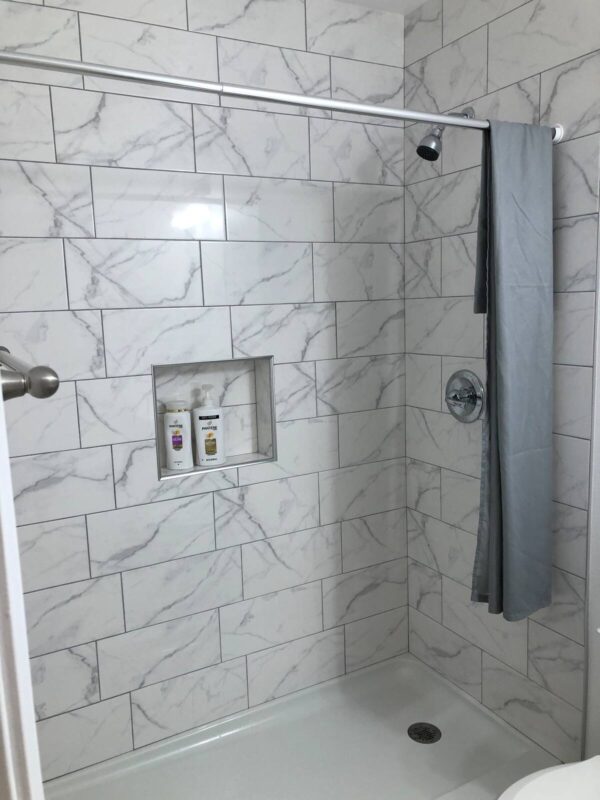 A bathroom with marble tile and a shower.