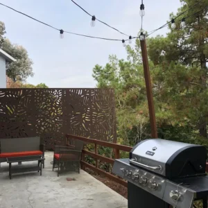 A grill on the patio of an outdoor room.