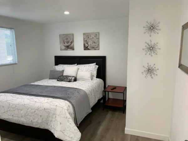 A bedroom with a bed, nightstand and two wall hangings.