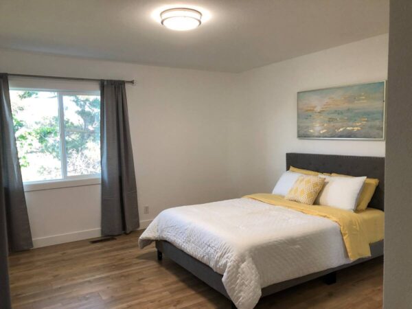 A bedroom with a bed, window and wooden floors.