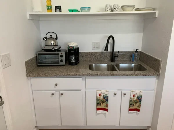 A kitchen with white cabinets and black appliances.