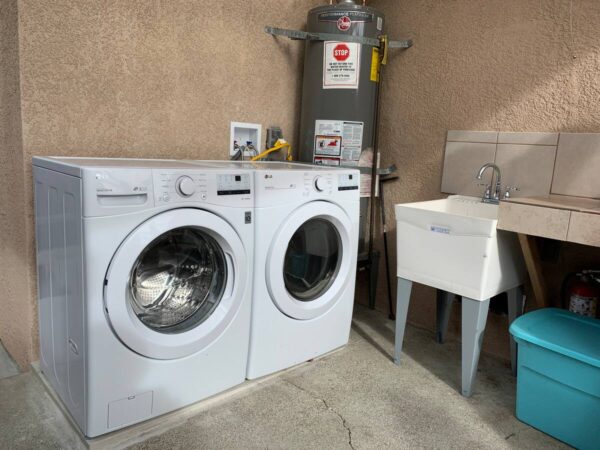 A washer and dryer in the garage next to a sink.