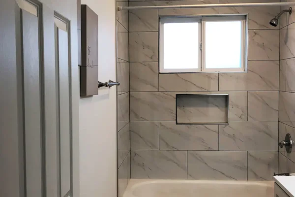 A bathroom with marble tile and a window.