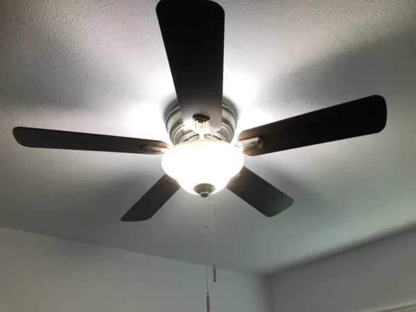 A ceiling fan with lights on in the room.