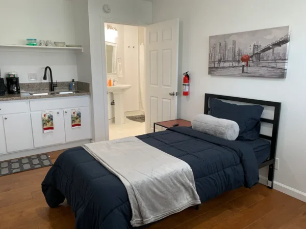 A bedroom with a bed, sink and mirror.