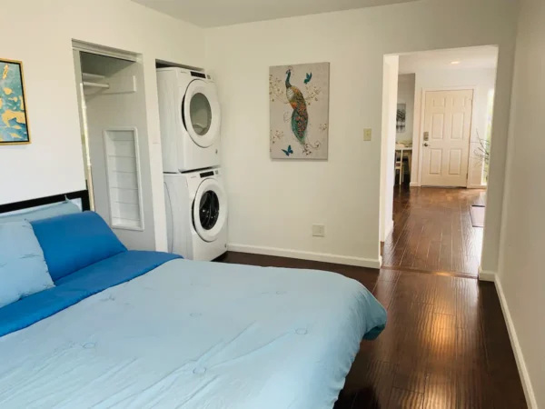 A bedroom with hardwood floors and washer dryer.