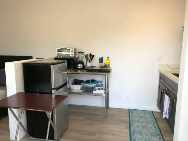 A kitchen with a microwave, sink and table.