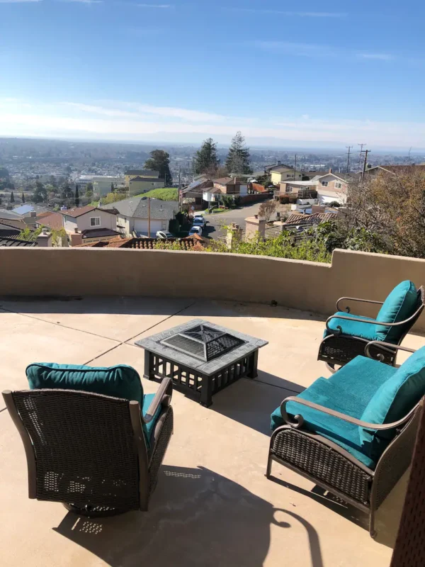 A patio with chairs and fire pit overlooking the city.