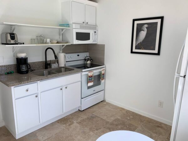 A kitchen with white cabinets and black counter tops.